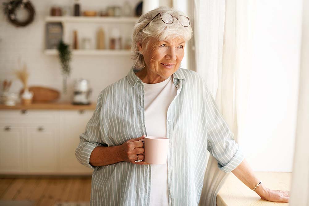 Ältere Frau mit Kaffee in der Küche: Sie macht sich Gedanken wegen Mangelernährung und Gewichtsabnahme im Alter